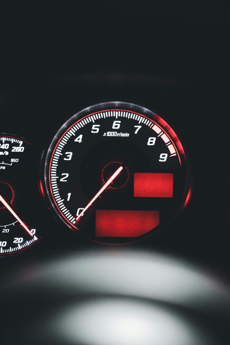 Detailed view of a car speedometer with red illumination, showcasing vehicle instrumentation at night.